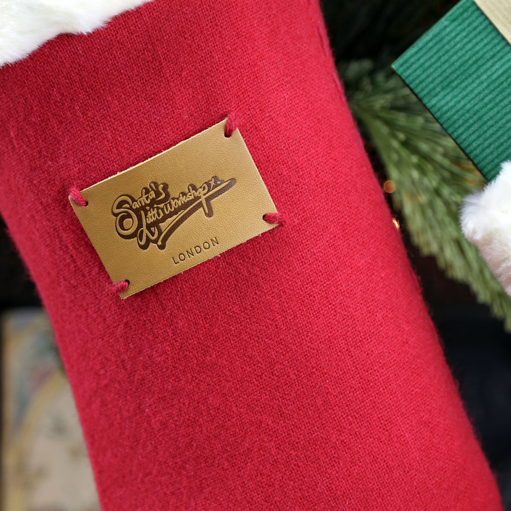 The softest merino wool traditional design Christmas stocking, a detail picture of the handmade leather patch and the high quality faux fur